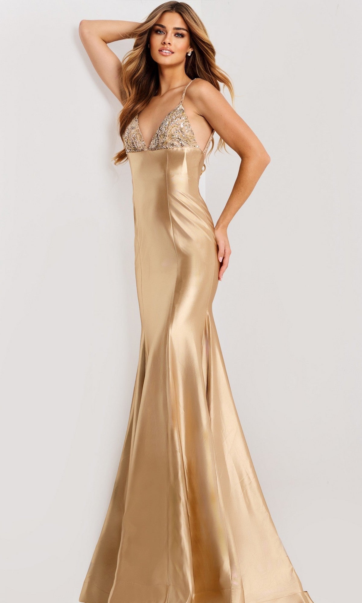 A woman models the Jovani 48733 long prom dress, featuring gold satin fabric, a sequined bodice, thin straps, and a mermaid silhouette against a plain background.